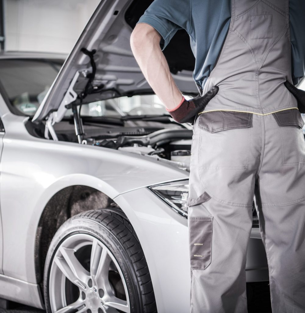 Modern Car Warranty Recall Fix. Mechanic in Front of the Vehicle in the Authorized Service Center.